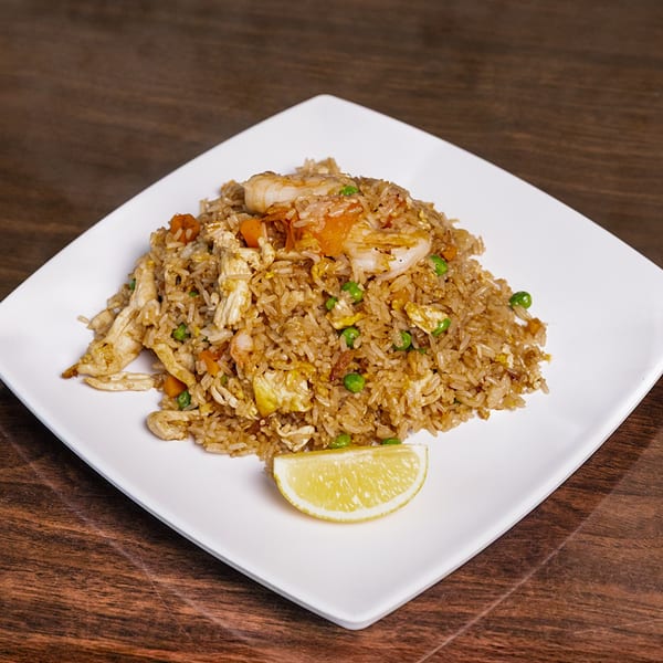 Thai Palace MD's fried rice with chicken, shrimp, peas, carrots, and egg, garnished with a lemon wedge.